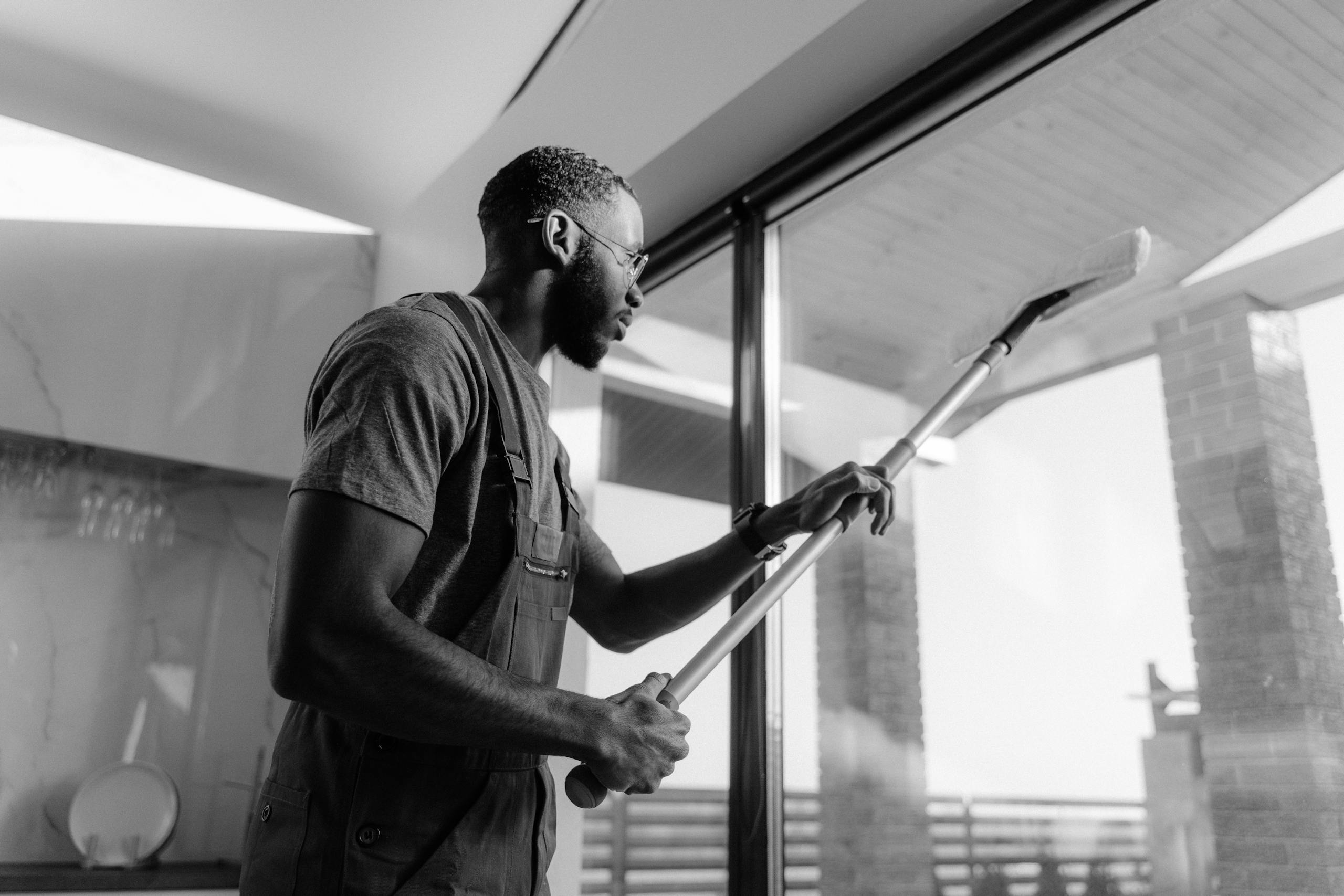 A professional cleaner wiping large glass panels with precision inside a modern building.