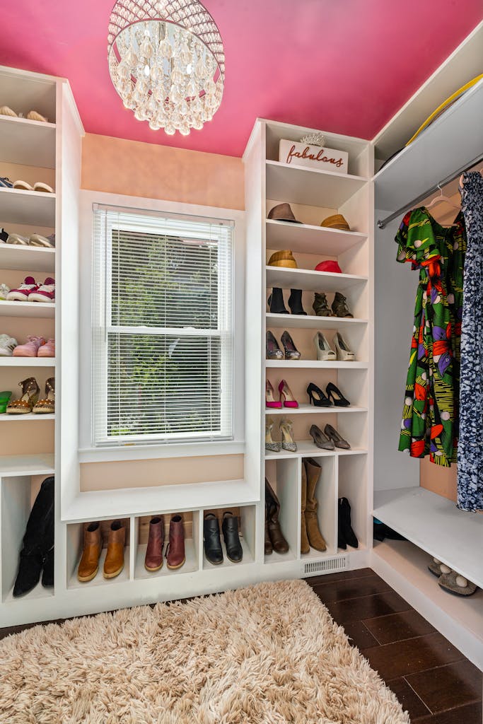 Elegant walk-in closet featuring an array of shoes and colorful dresses, with plush carpet flooring and natural lighting.