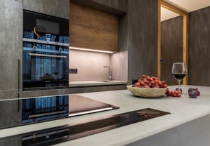 Sleek modern kitchen featuring luxury appliances, a bowl of grapes, and a glass of wine on the counter.