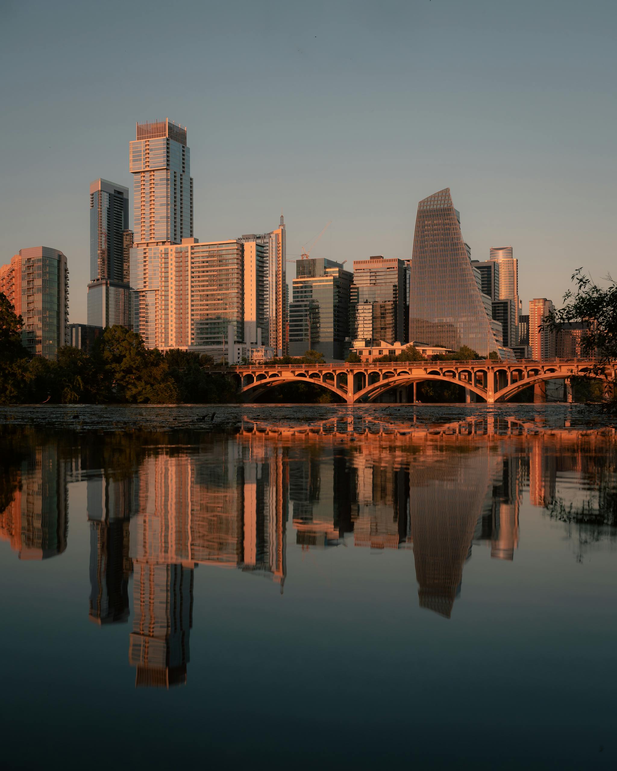 Stunning view of Austin's skyline and bridge reflected in the river at sunset, capturing urban serenity.